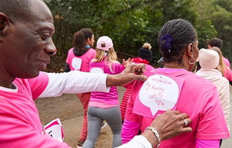Race for Life participants walking in a park. One is attaching a back sign which says I Race for Life for my aunty Julie.